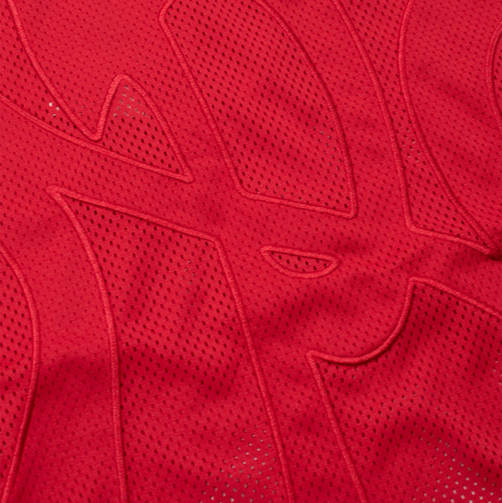 Detailed macro perspective of the center chest embroidery on the red No Problemo NYP Sports Mesh Jersey, showing the textured red fabric patch precision-stitched along the edges to form the intertwined NYP varsity monogram set over the perforated athletic eyelet mesh.