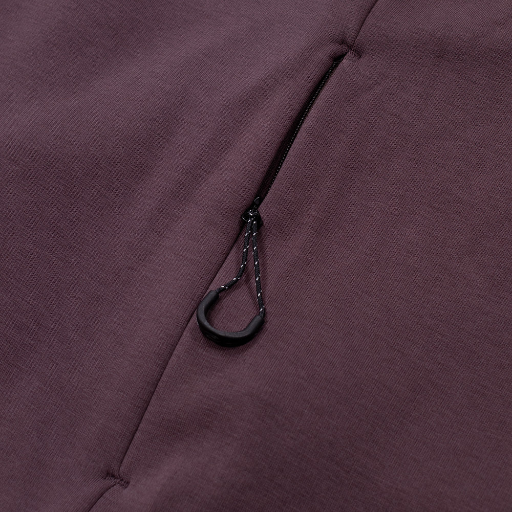 Detailed macro shot of the side seam utility pocket on the Oakley FGL Slick Fleece Hoodie, showing the concealed reverse zipper track integrated into the seam, equipped with a speckled paracord loop and contoured matte black plastic pull tab.