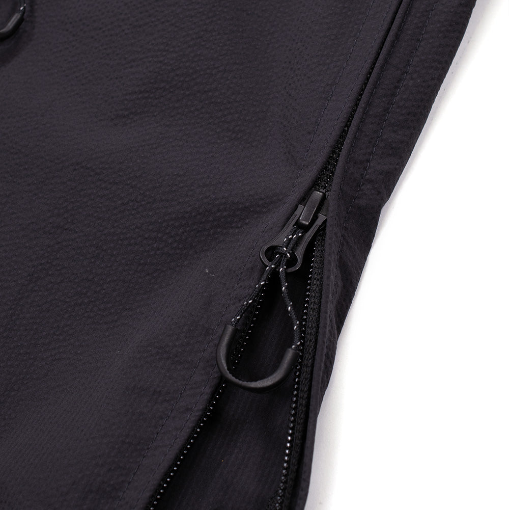 Macro studio perspective of the side seam entry closure on the Oakley FGL Stroke Anorak in Phantom, highlighting the robust reverse-coil side zipper for easy on-and-off access, equipped with a durable pull tab and reinforced lower hem construction.