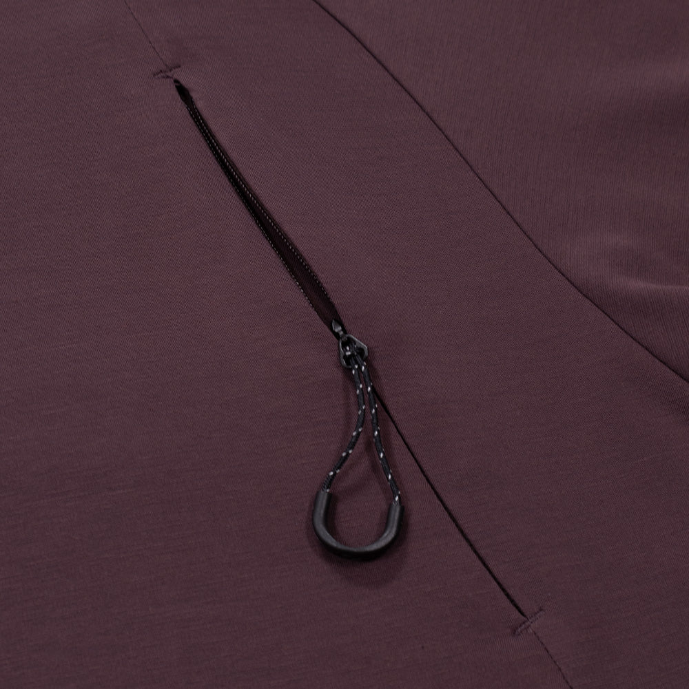 Detailed macro perspective of the chest pocket on the Oakley FGL Union SS Tee, focusing on the streamlined concealed zipper track embedded along the curved seam, fitted with a black speckled paracord pull loop and ergonomic plastic grip