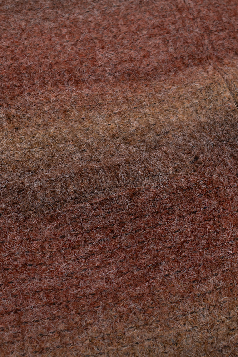 Macro detail shot of the brushed knit fabric on the Obey Anton Gradient Cardigan, showcasing the fuzzy mohair-like texture blending acrylic, polyester, nylon, and wool yarns in an earthy brown gradient beside a front welt pocket seam.