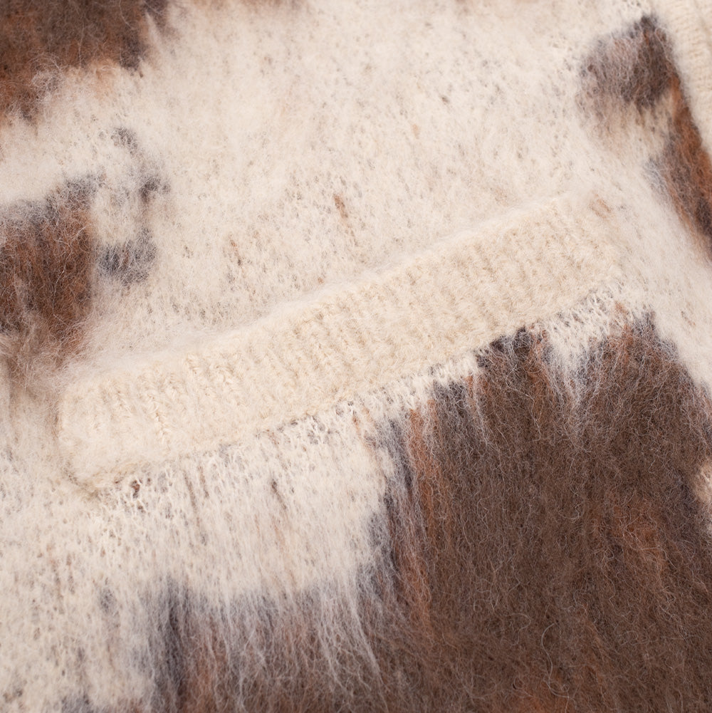 Detailed close-up shot of the front waist pocket on the Obey Cow Pattern Zip Sweater, focusing on the horizontally ribbed welt pocket trim set seamlessly into the shaggy, textured brown and cream cow pattern knit fabric.