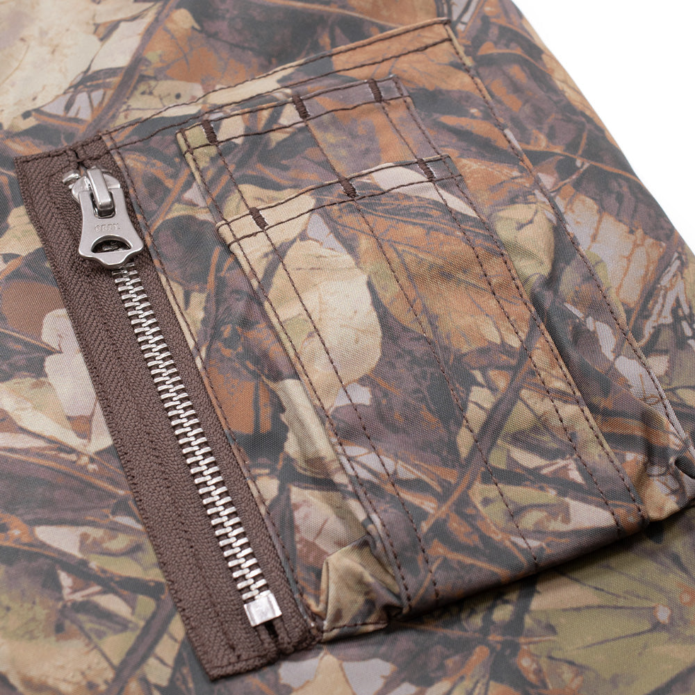 Close-up studio view of the left sleeve utility pocket on the Obey N-2B Short Parka, featuring traditional military MA-1 flight jacket pen slots and a vertical metal zip pocket with an engraved OBEY zipper pull.