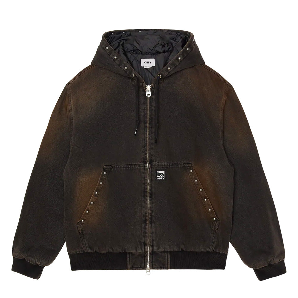 Front flat lay view of the Obey Studded Zip Up Jacket in black rust wash denim, featuring a workwear hooded silhouette with heavy fading, antique round metal studs trimming the hood brim and split kangaroo pockets, full front silver metal zipper, dark ribbed waistband and cuffs, quilted interior lining, and a woven black Obey Eyes logo patch on the front pocket.