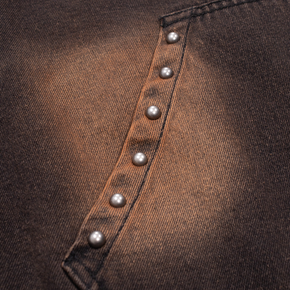 Macro studio perspective of the pocket trim on the Obey Studded Zip Up Jacket, detailing the clean row of round silver metallic dome studs anchored along the reinforced slanted pocket welt against the gradient black-to-copper wash of the cotton denim.