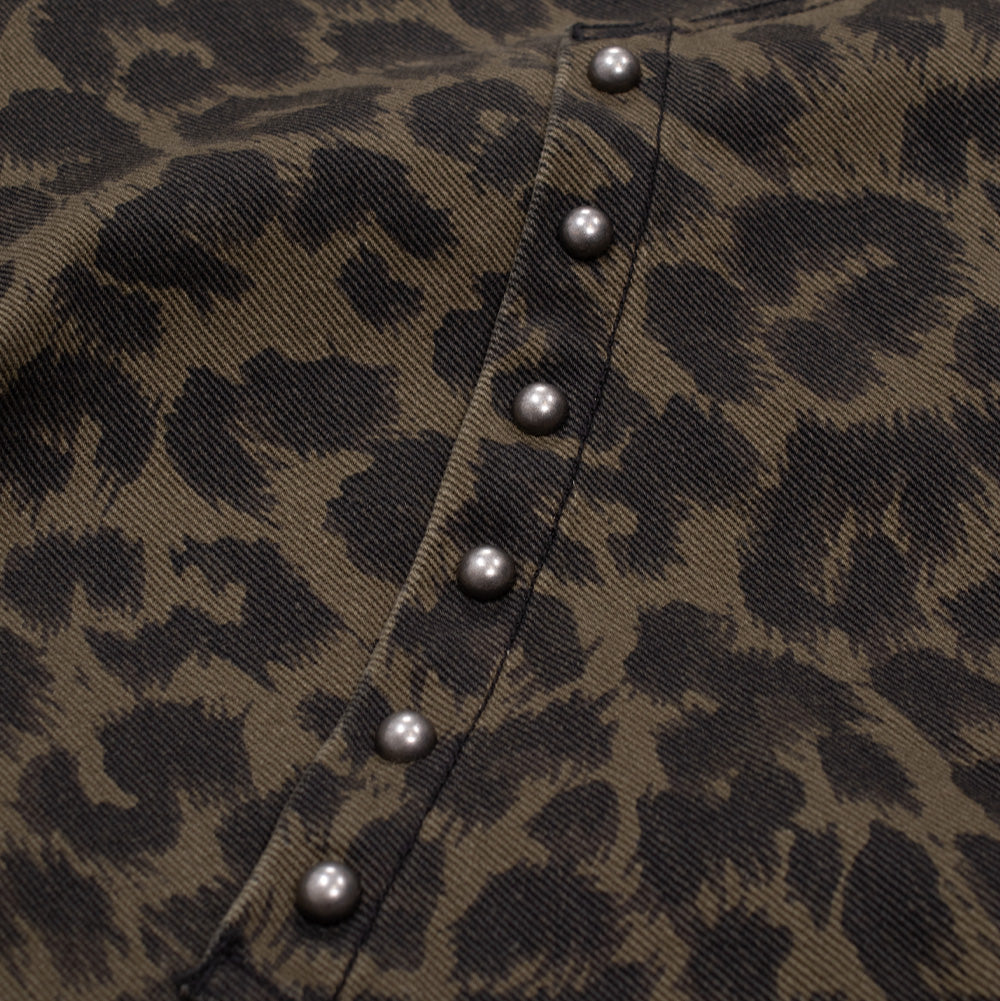 Macro studio perspective of the pocket trim on the Obey Studded Zip Up Jacket in Dark Leopard, detailing a vertical row of antique silver round metal studs pressed along the reinforced slanted pocket seam of the leopard-patterned twill cotton.