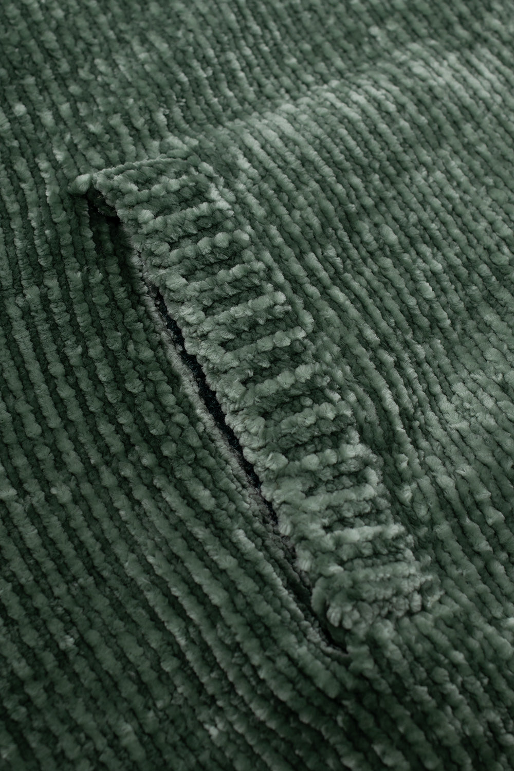 Detailed shot of the front side pocket construction on the Obey Varen Zip Up Sweater, highlighting the reinforced vertical ribbed welt pocket opening and the velvety texture of the forest green knit.