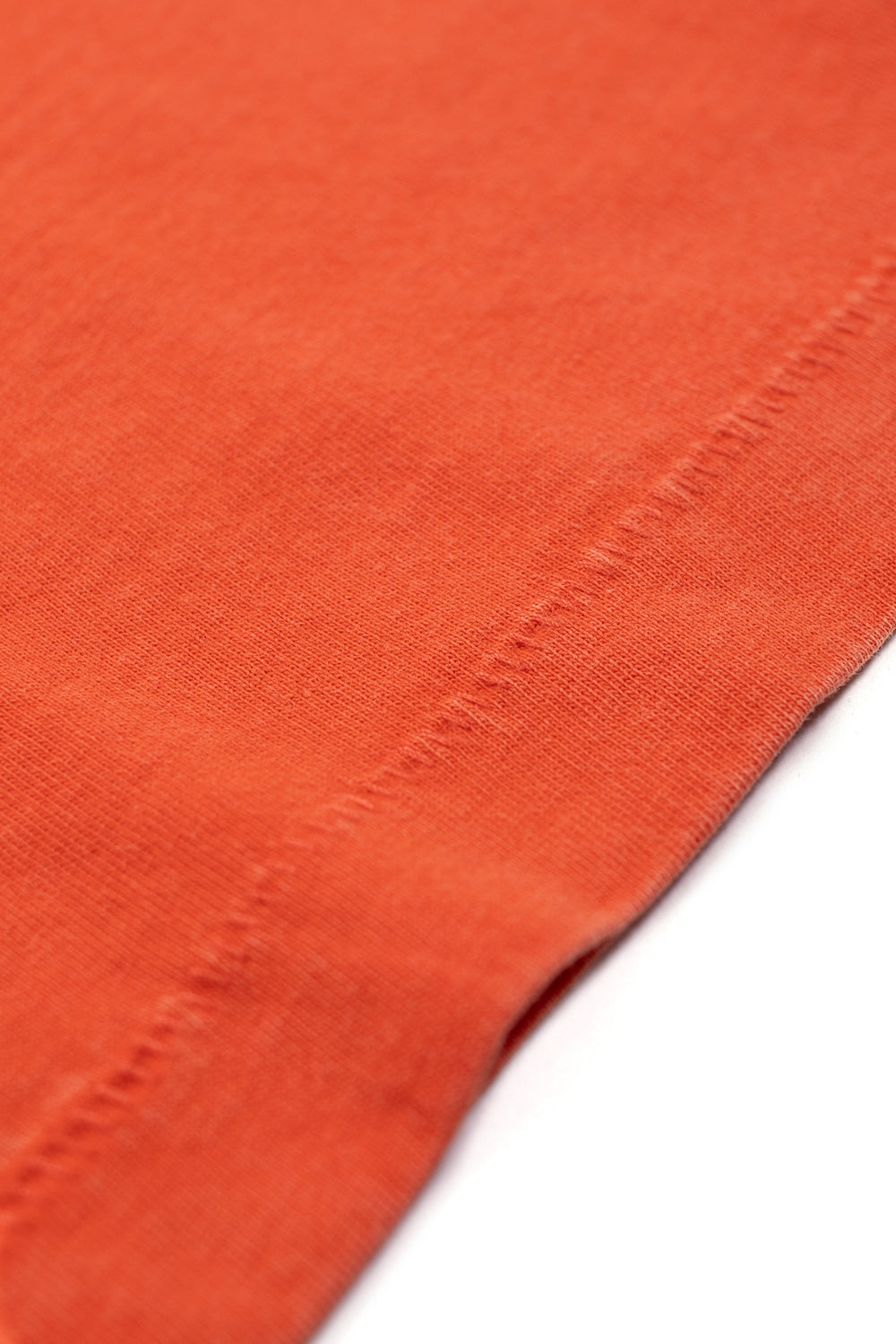 Macro detail of OTW by Vans x Julian Klincewicz Mandarin Red t-shirt highlighting soft 100% cotton fabric, single stitch construction and retro washed texture for everyday skate style