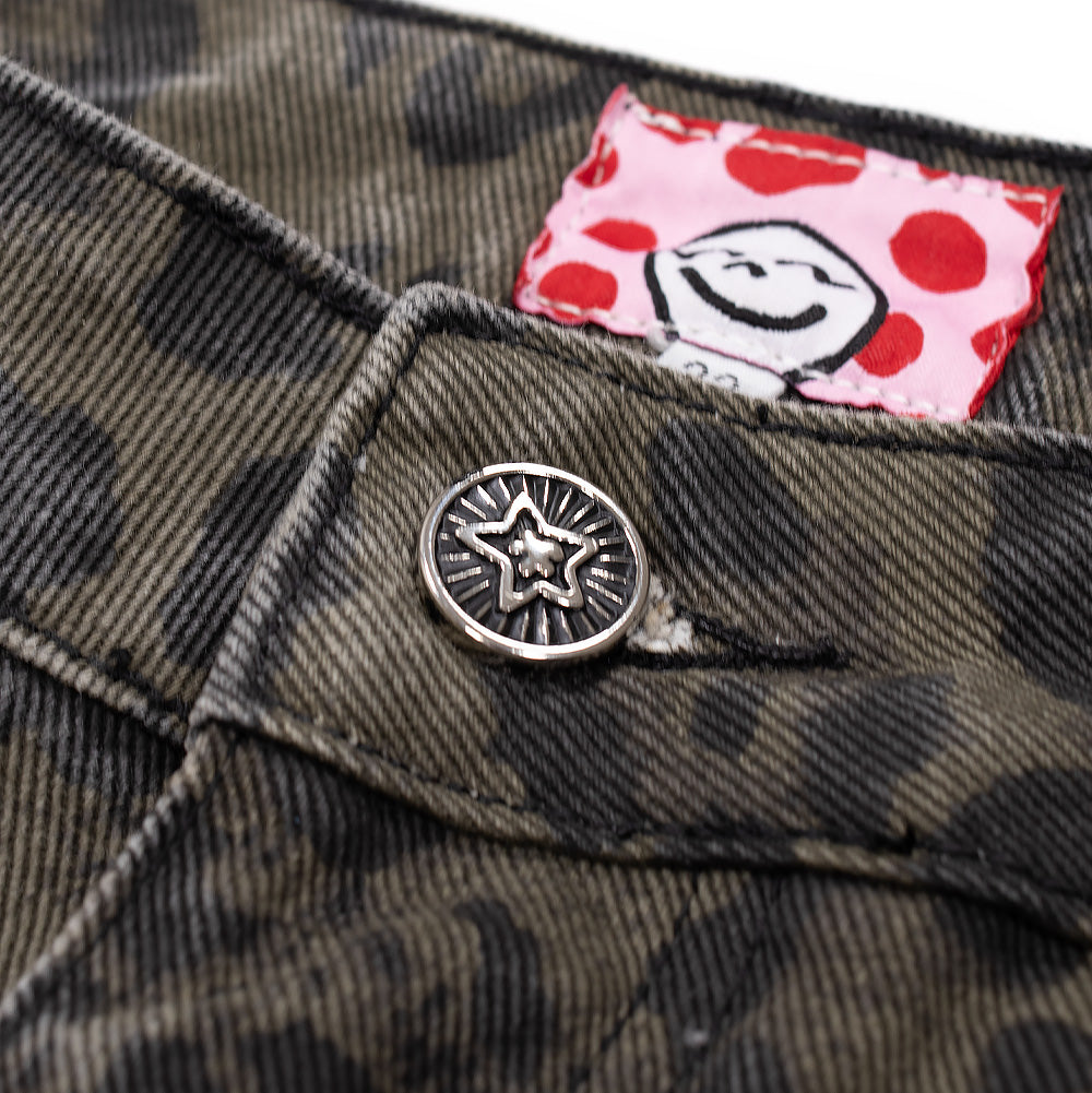 Detailed macro studio close-up of the front waistband closure on the Starteam Leopard Star Jeans, focusing on the polished silver metallic tack button embossed with a radiating Starteam star emblem, accompanied by the playful interior red polka-dot waistband lining featuring a cartoon face tag and heavy diagonal denim twill stitch construction.