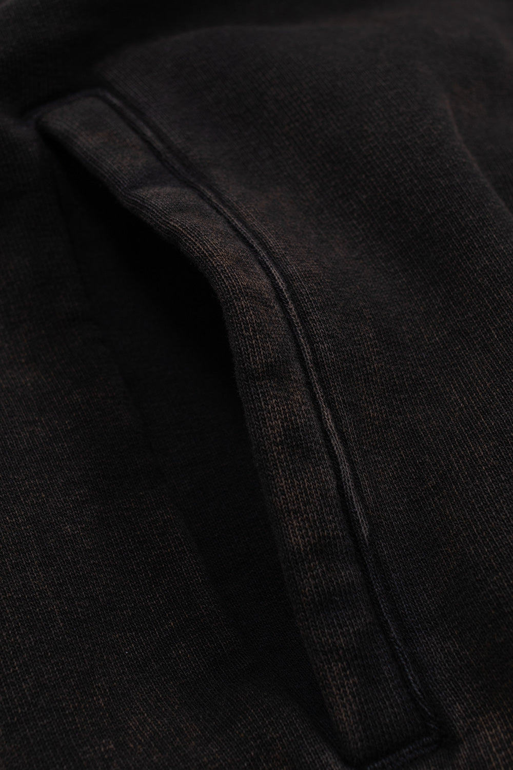 Macro detail of the side pocket and acid wash cotton texture on the The Trilogy Tapes Dash Line Hood Black, showcasing heavyweight fleece fabric, washed black finish, relaxed fit construction and premium contemporary streetwear quality.