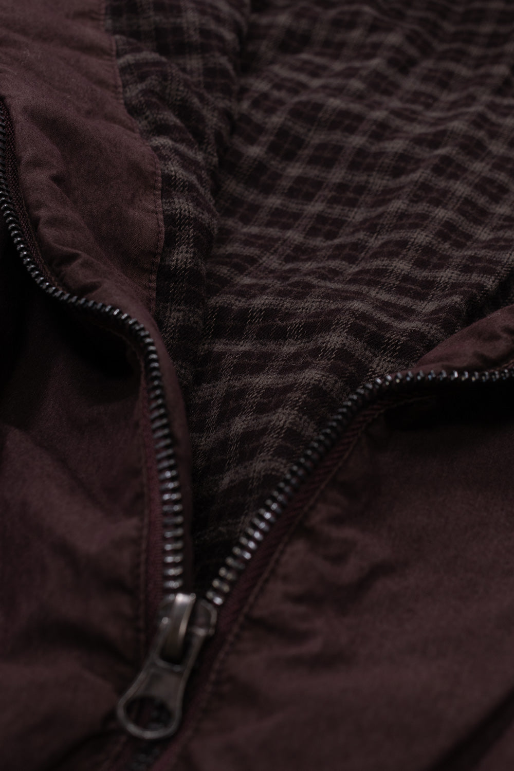 Detailed view of the unzipped front placket on the Umbro Sunday Masked Jacket, displaying the heavy-duty metal zipper slider, zipper teeth, and the dark brown and black yarn-dyed plaid cotton lining