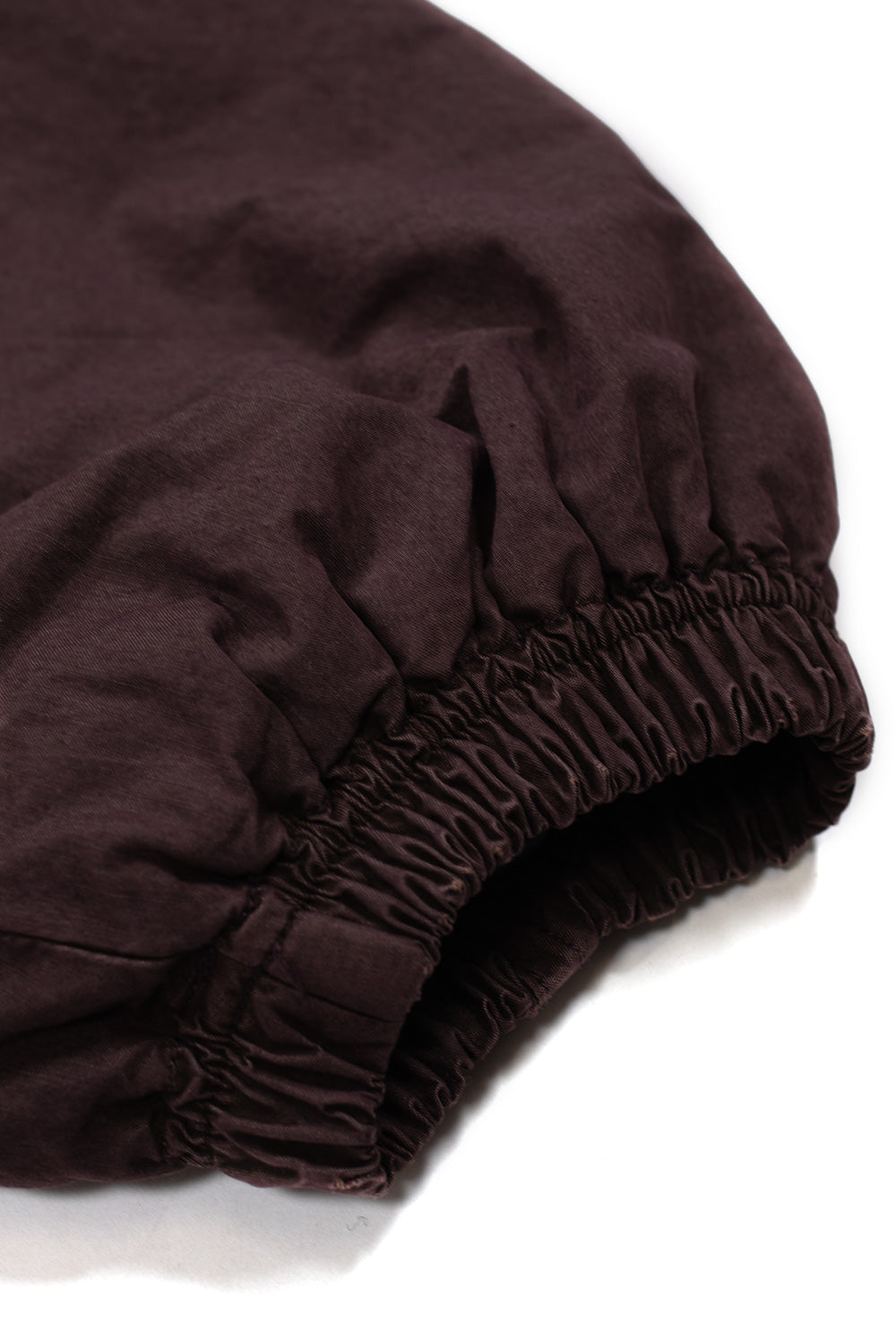 Macro detail of the gathered elastic sleeve cuff on the plum grey Umbro Sunday Masked Jacket, highlighting the dense shirred stitching and the washed, soft-finish cotton fabric texture