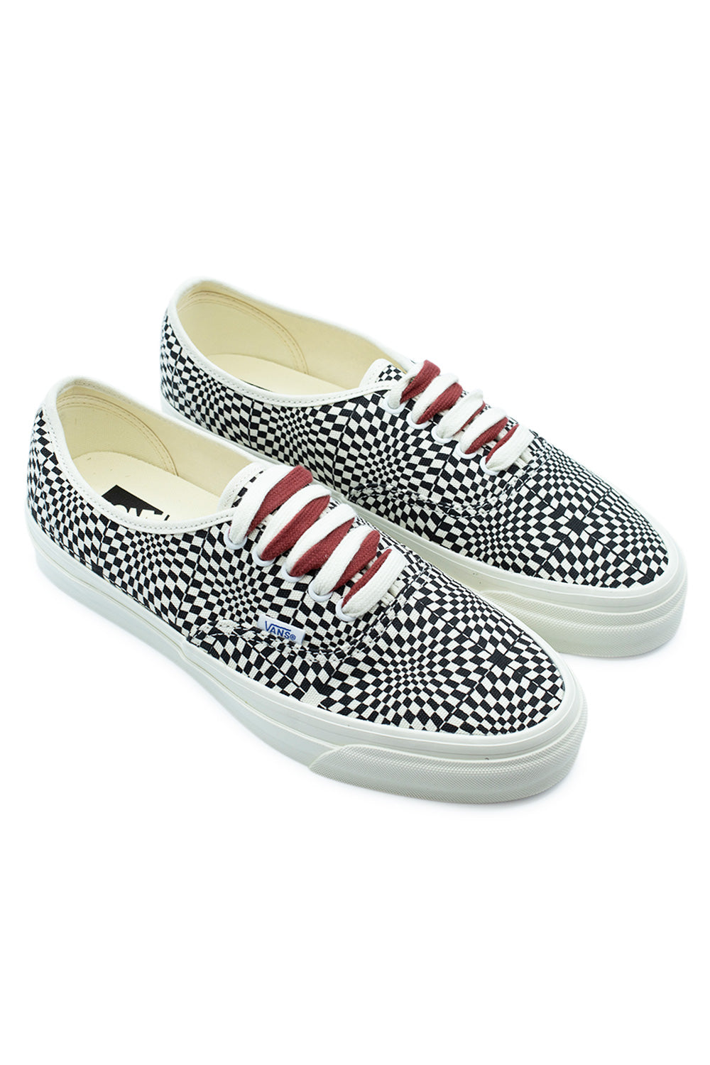 Three-quarter perspective studio shot of both Vans LX Authentic 44 Heritage Black shoes, displaying the unique optical checkerboard aesthetic, 90s Osnaburg-inspired high foxing tape, and crisp low-cut profile.