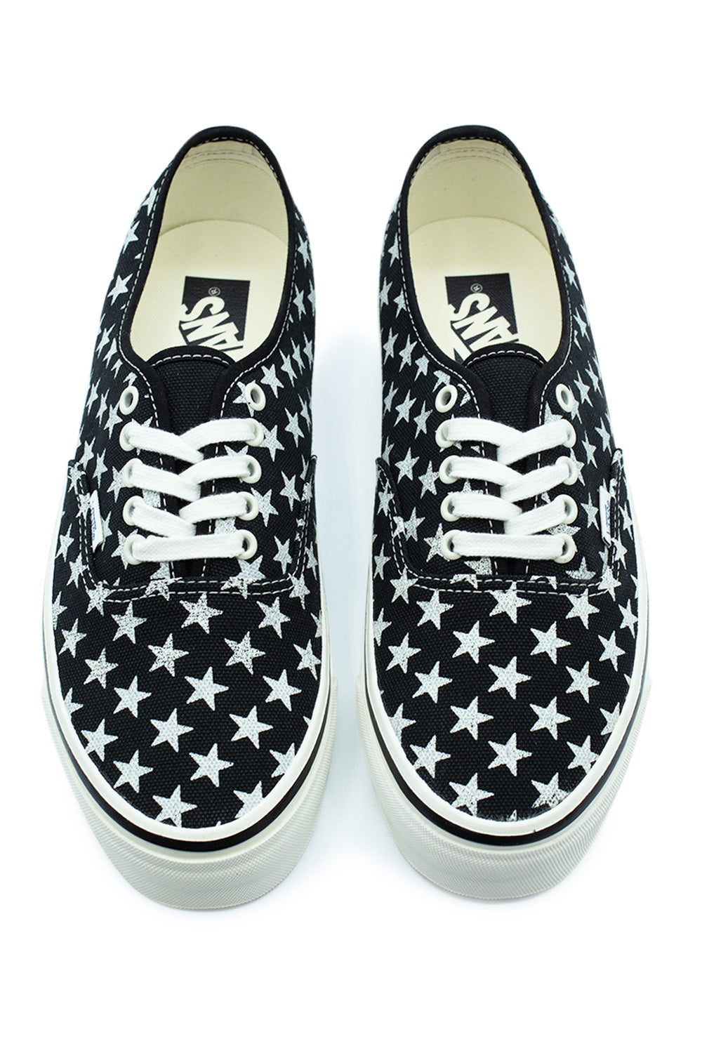 Top-down view of a pair of Vans LX Authentic 44 low-top canvas shoes, displaying the dense white star print pattern on black fabric, clean white laces, white metal lace eyelets, and cream insoles printed with the black vintage Vans logo.