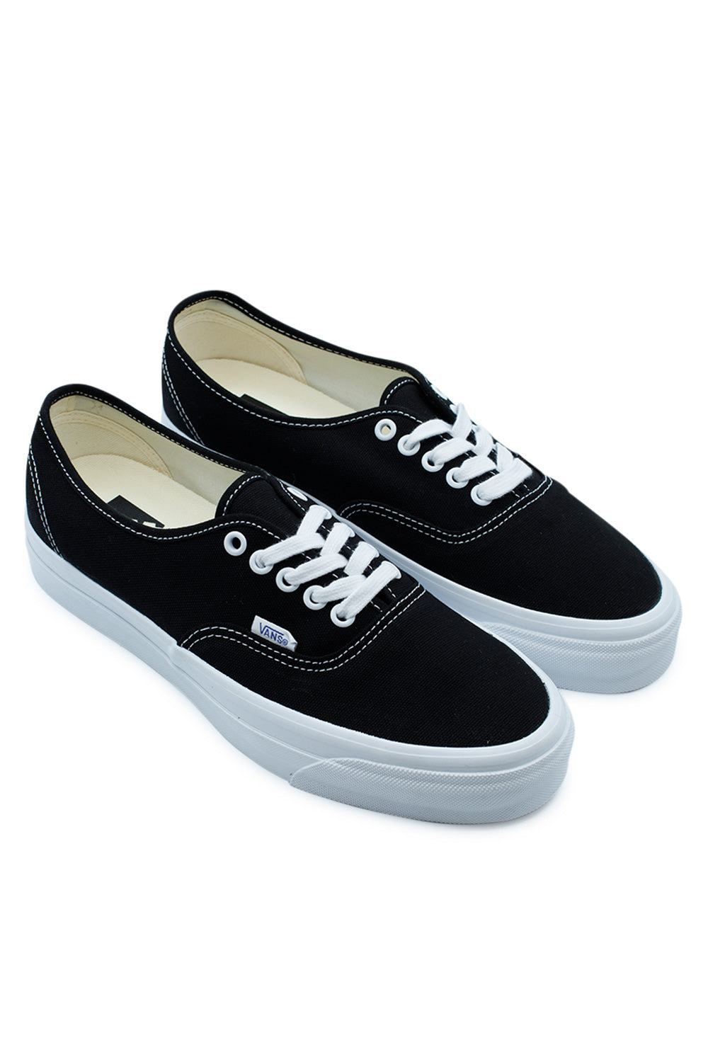 Angled view of the Vans LX Authentic Reissue 44 sneakers in Black / White with classic low-top canvas silhouette, premium vintage foxing, white rubber midsole, reinforced construction and iconic skate shoe styling rooted in California skate culture and Vans heritage.