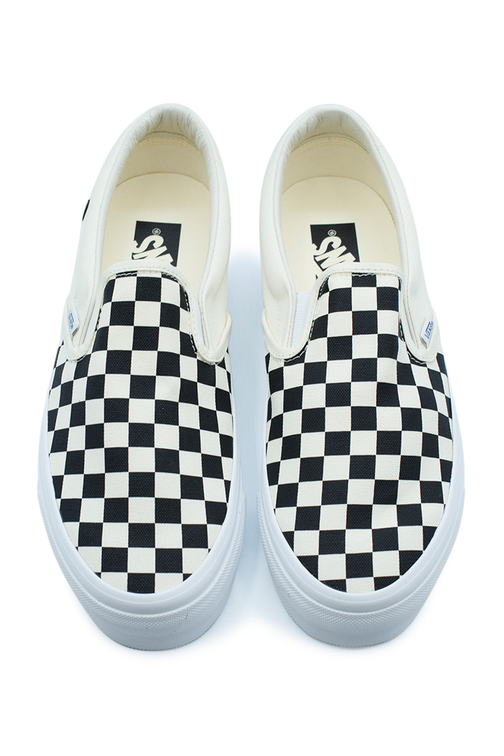Top-down view of a pair of Vans LX Slip-On Reissue 98 shoes, highlighting the classic black and off-white screen-printed checkerboard pattern on the canvas upper.