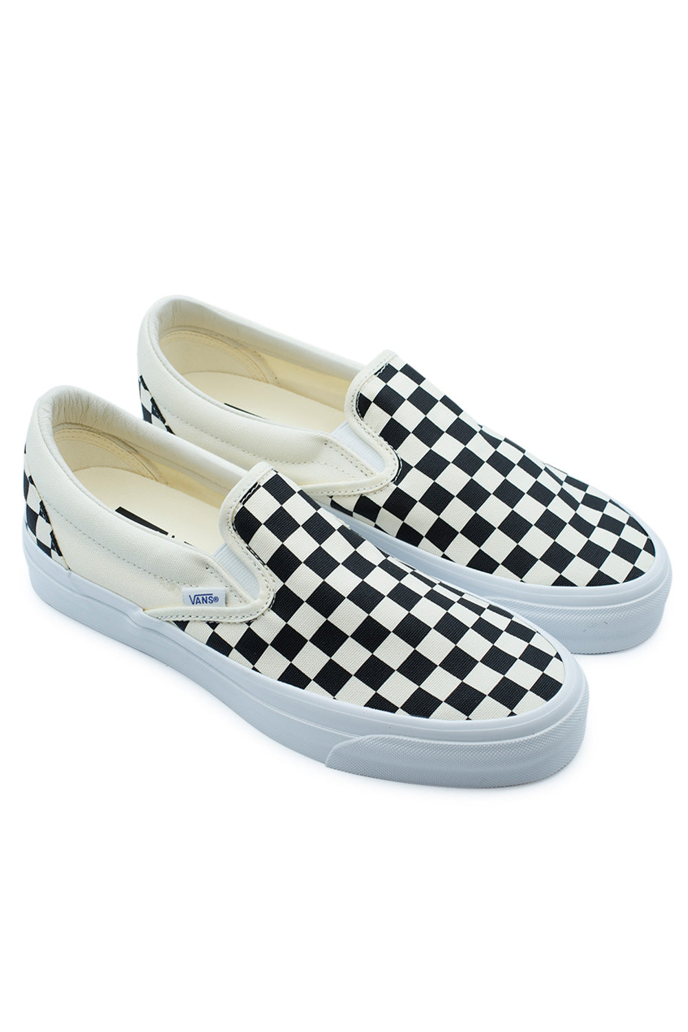 Studio shot of a pair of Vans LX Slip-On Reissue 98 Checkerboard sneakers placed together at an angle, displaying the premium slip-on design and off-white elastic accents.