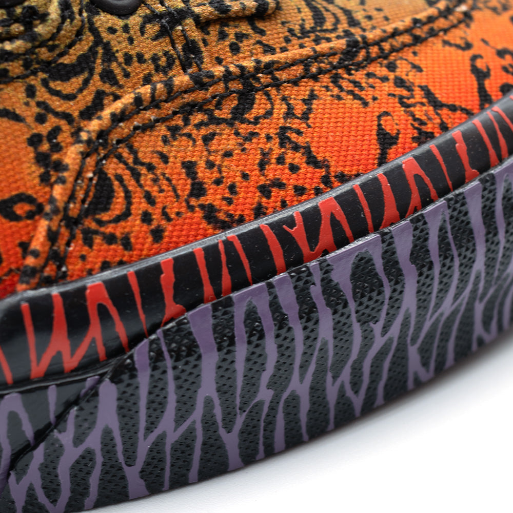 Macro studio view of the vulcanized foxing tape on the Vans OTW x Chito Half Cab 33, highlighting the dual-tone tribal barbed wire graphics printed in vibrant red and purple over textured black rubber, bonded along the edge of the dense orange skull-printed canvas upper.