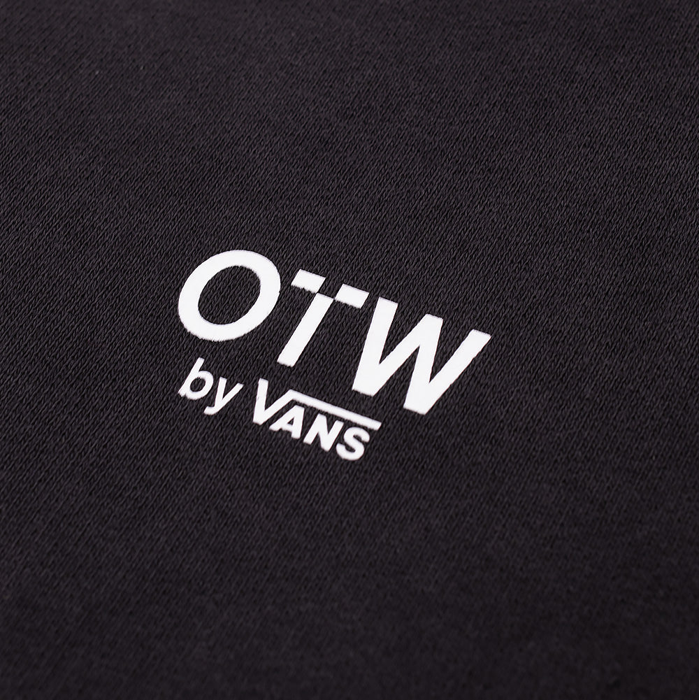 Macro studio view of the center chest on the Vans OTW x Chito Sweatshirt, detailing the crisp, fine-line white screen print of the modern "OTW by VANS" branding against the textured, mineral-washed black cotton fleece fabric.