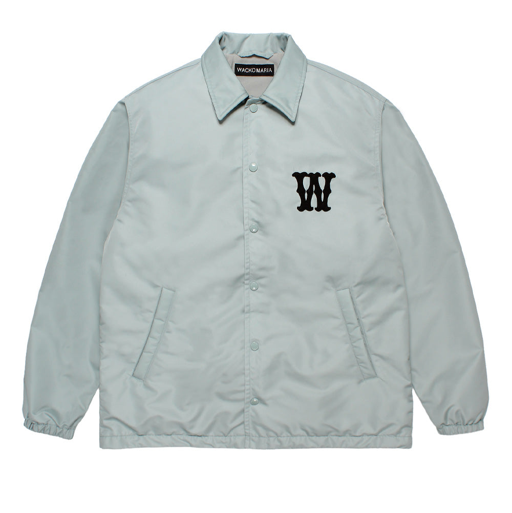 Front flat lay studio view of the light grey Wacko Maria Coach Jacket Type 2, featuring a tonal snap-button front closure, slanted welt hand pockets, an inner woven neck label, and a single black gothic felt "W" applique patch stitched onto the left chest.