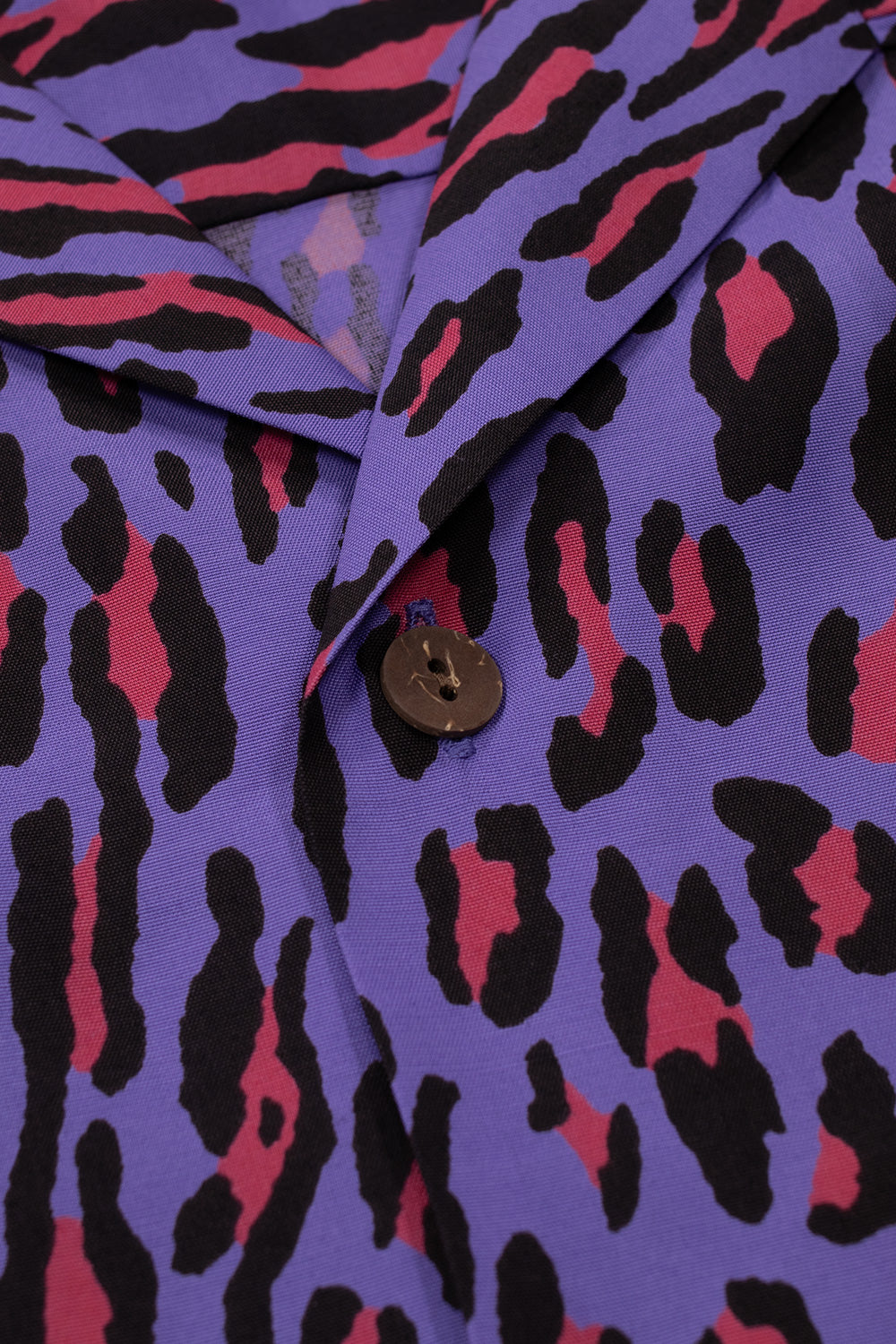 Close-up detail of the camp collar and the top wooden button on the purple Wacko Maria rayon Hawaiian shirt.