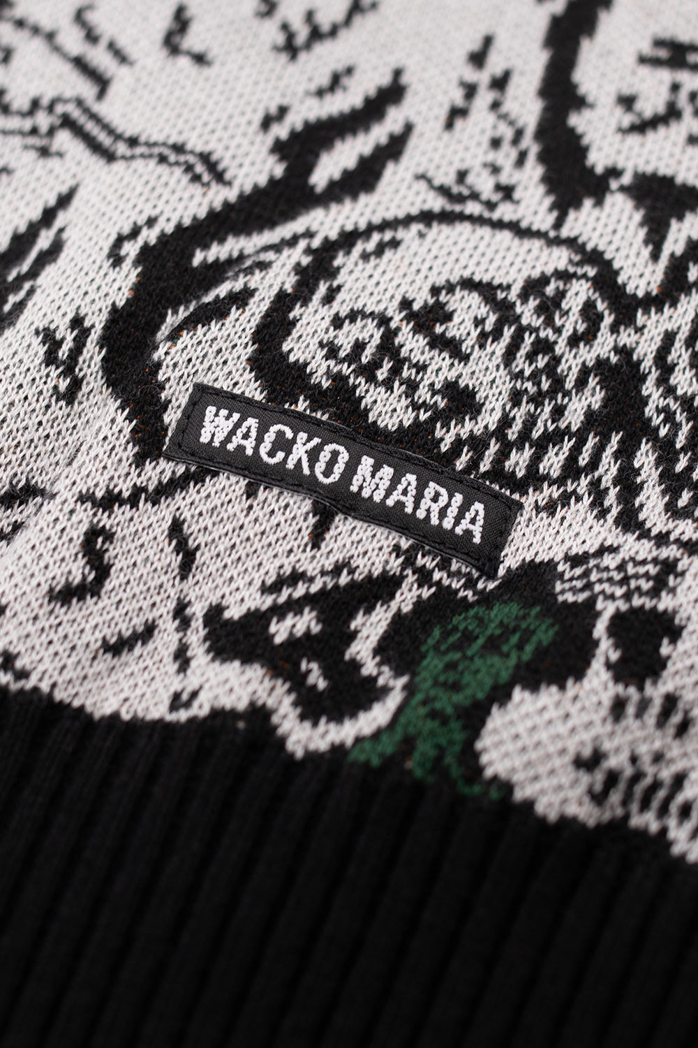Wacko Maria woven side label detail on jacquard knit sweater, showcasing premium craftsmanship, designer streetwear branding and Japanese made garment quality