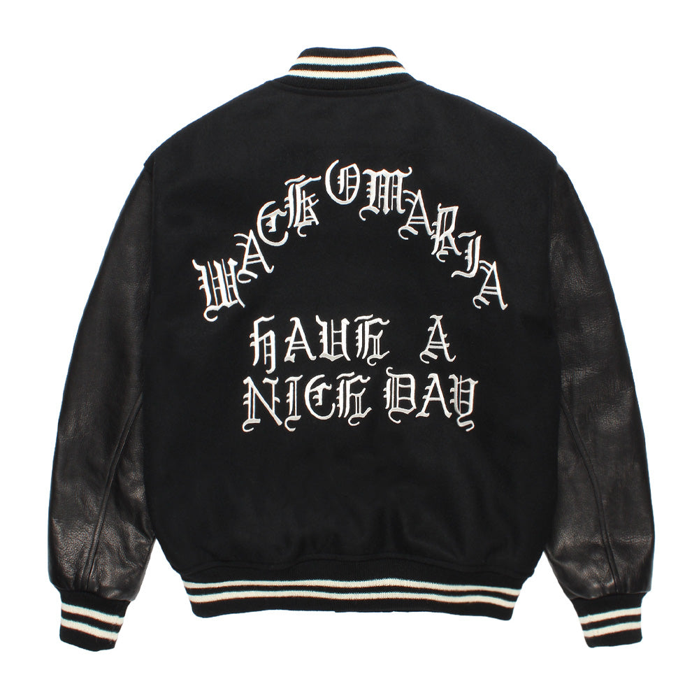 Back studio view of the Wacko Maria Leather Varsity Jacket Type 3 in all-black, displaying the heavy wool melton body and genuine cowhide leather sleeves, finished with striped ribbed collar and cuffs, and large arched white gothic Old English embroidery reading "WACKO MARIA HAVE A NICE DAY".