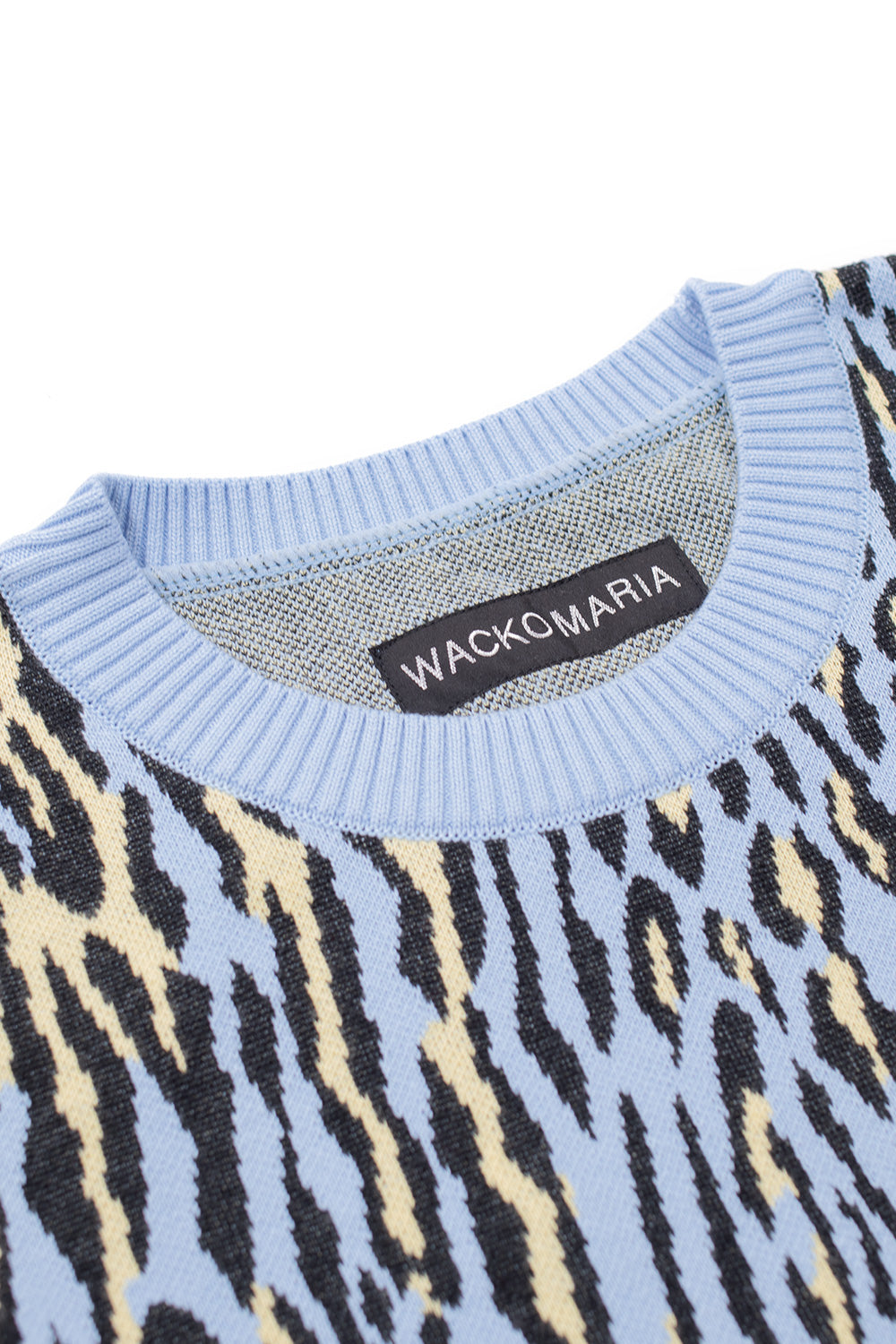 Close-up of Wacko Maria crewneck label on light blue leopard jacquard sweater, soft 100% cotton knit, ribbed collar detail, luxury Japanese designer streetwear craftsmanship