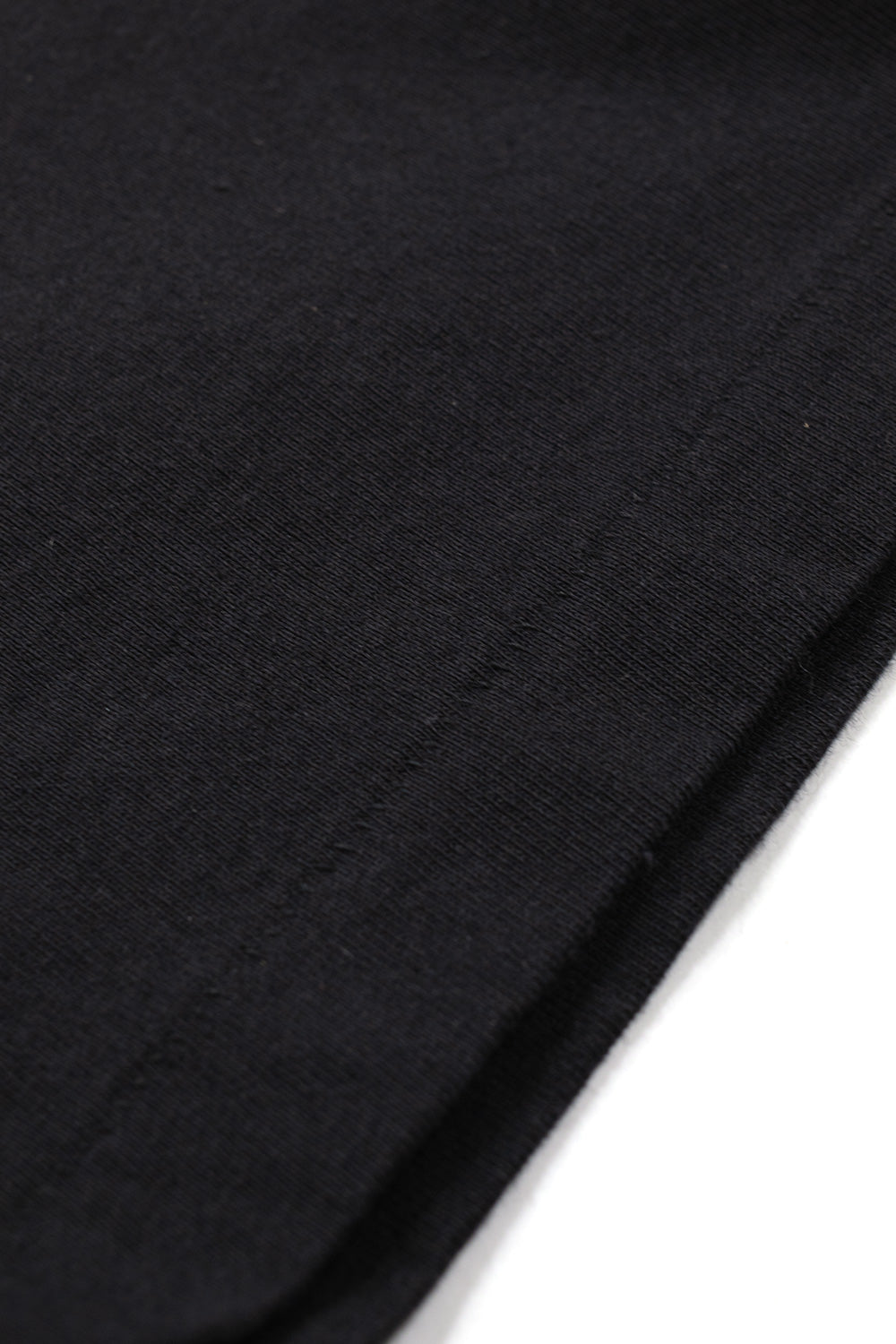 Detailed view of the premium quality vintage single-stitch hem on the black Wacko Maria washed heavy weight cotton t-shirt.