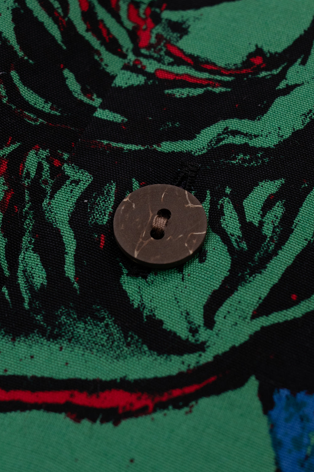 Macro shot Wacko Maria Terrifier Hawaiian shirt wooden button on printed rayon fabric, high-quality construction, seamless pattern alignment on button placket