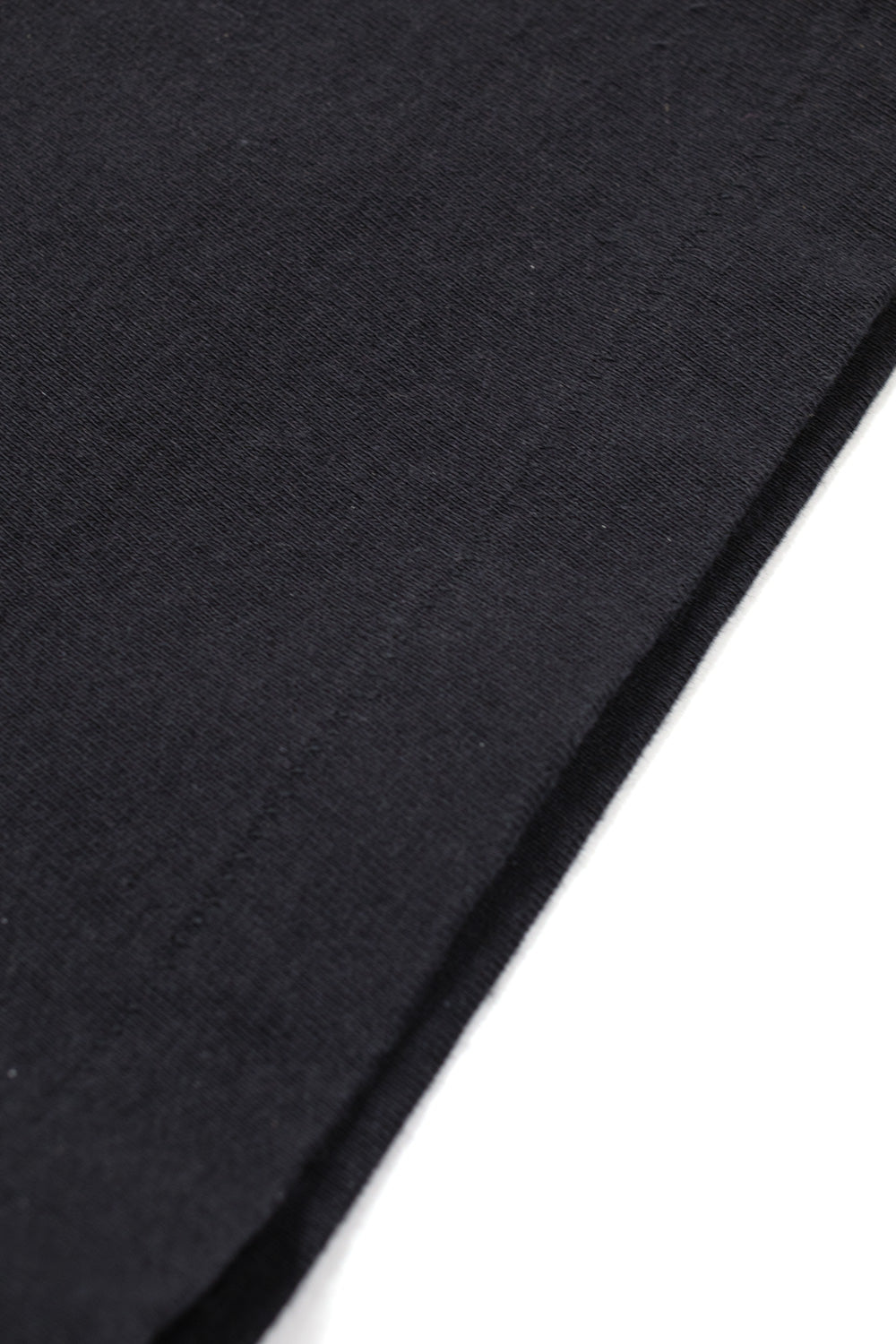 Macro shot of washed heavy cotton fabric and vintage single stitch hem on Wacko Maria x Terrifier black T-shirt, durable high-quality construction with soft worn-in feel