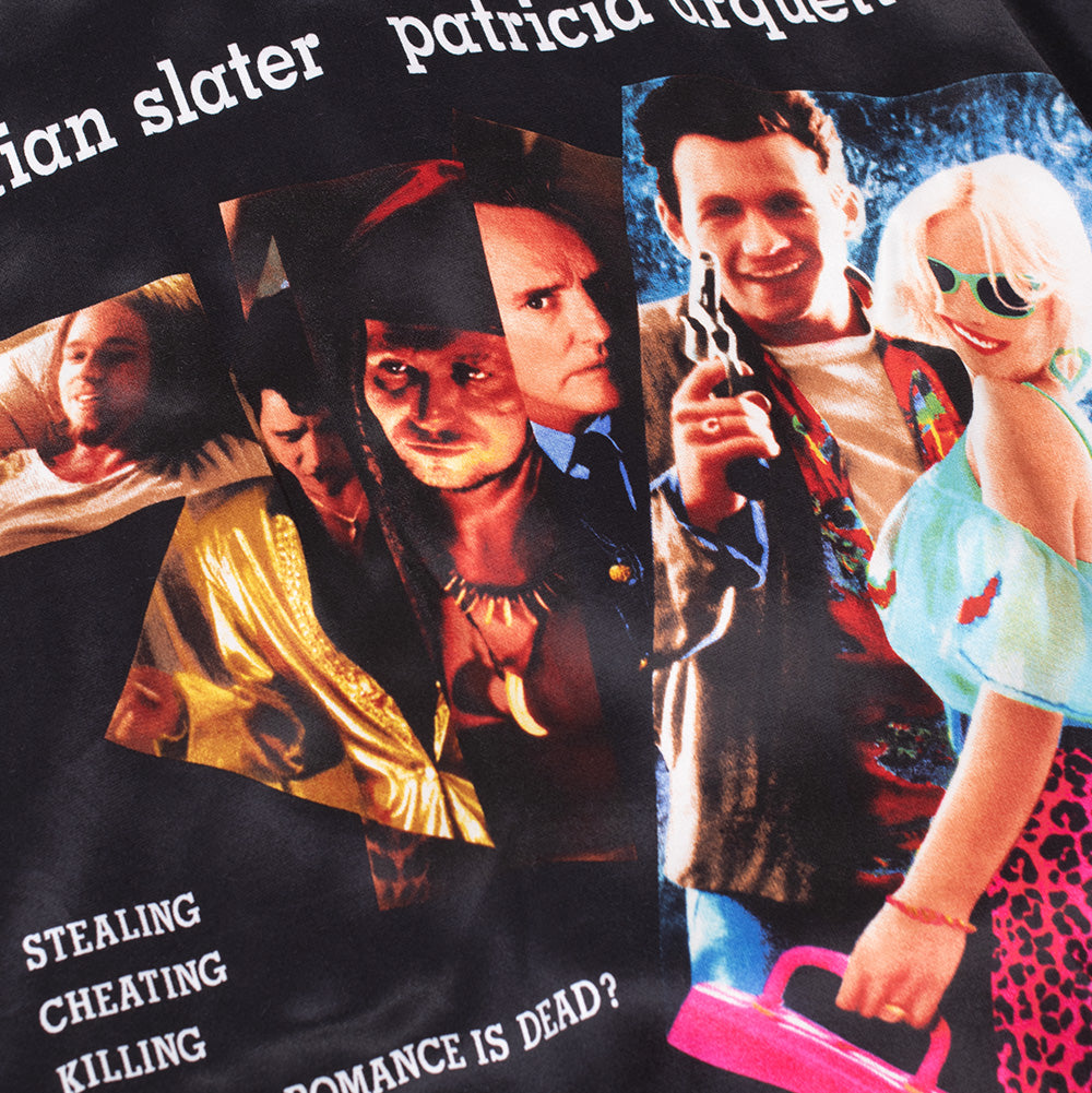 Macro studio view of the back graphic print on the black Wacko Maria x True Romance Ska Jacket, detailing the vibrant photographic collage of Clarence Worley and Alabama Whitman alongside iconic movie quote text printed on glossy satin.