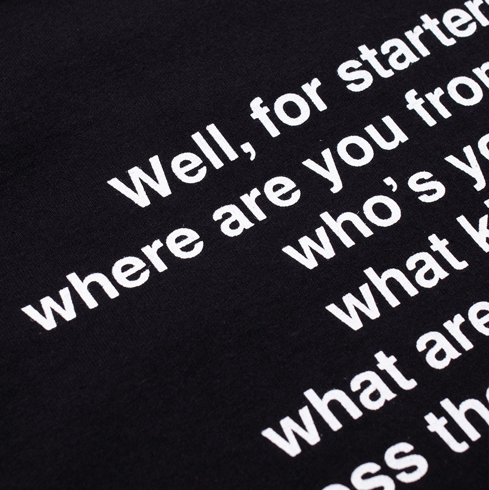 Macro perspective of the upper back typography on the Wacko Maria x True Romance T-Shirt, detailing the crisp white screen-printed movie quote text on washed, textured black heavyweight cotton fabric.