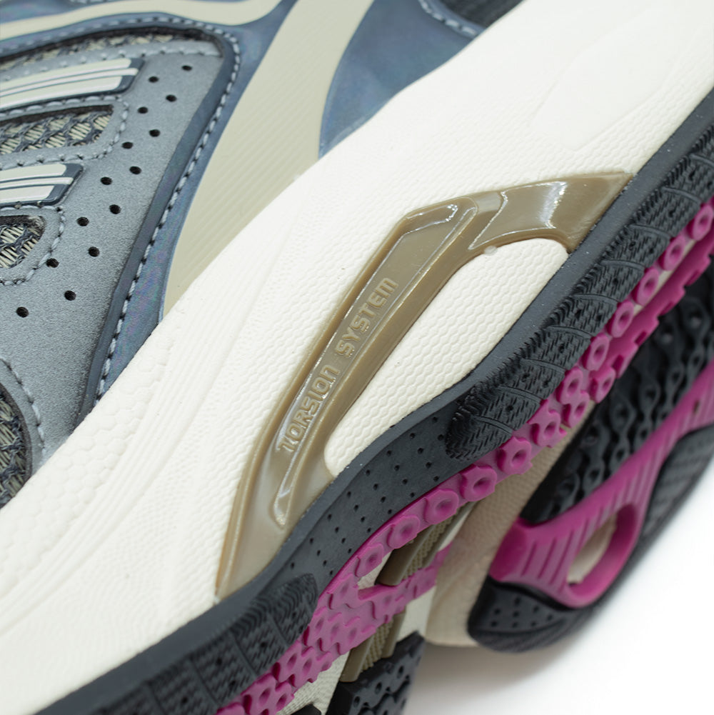 Macro studio perspective of the medial arch on the adidas Adistar Control 5, showcasing the molded olive TPU bridge embossed with "TORSION SYSTEM" lettering spanning the cream foam midsole, framed by textured high-density mesh and the fuchsia-accented rubber outsole base.