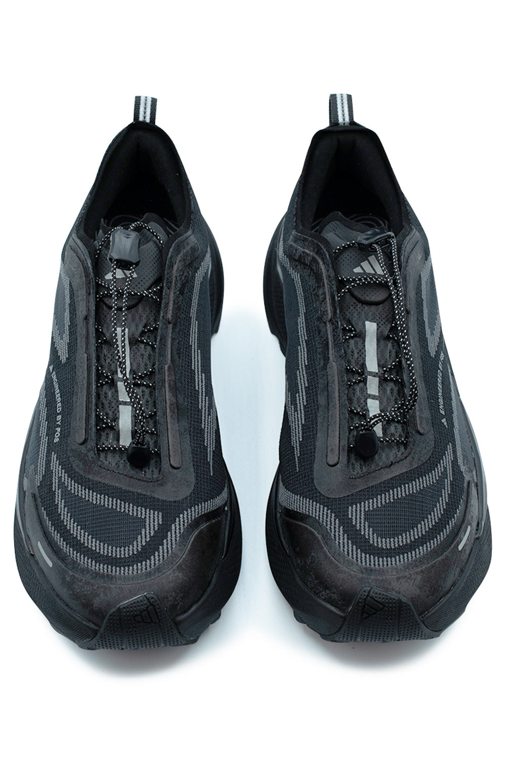Top-down view of a pair of Adidas Holo Peak shoes in Core Black, highlighting the technical quick-pull bungee speed lacing system with lace toggle, perforated tongue with subtle Adidas mountain logo, reinforced mudguard toe cap, and striped heel pull loops.