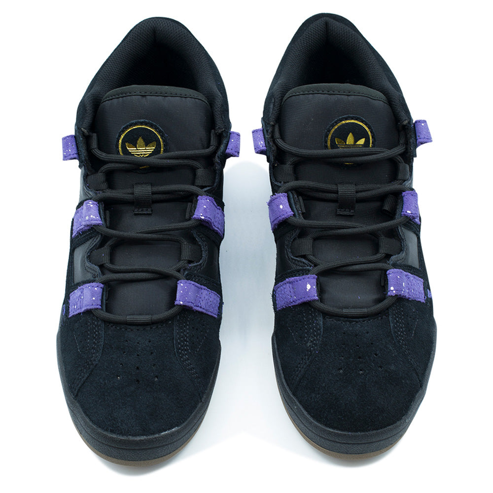Top-down studio view of the adidas Kader skate shoes, highlighting the perforated black suede toe boxes, wide ghillie lace loops integrated into purple hairy suede side straps, round black laces, and padded black nylon tongues adorned with circular gold metallic embroidered adidas Trefoil patches.