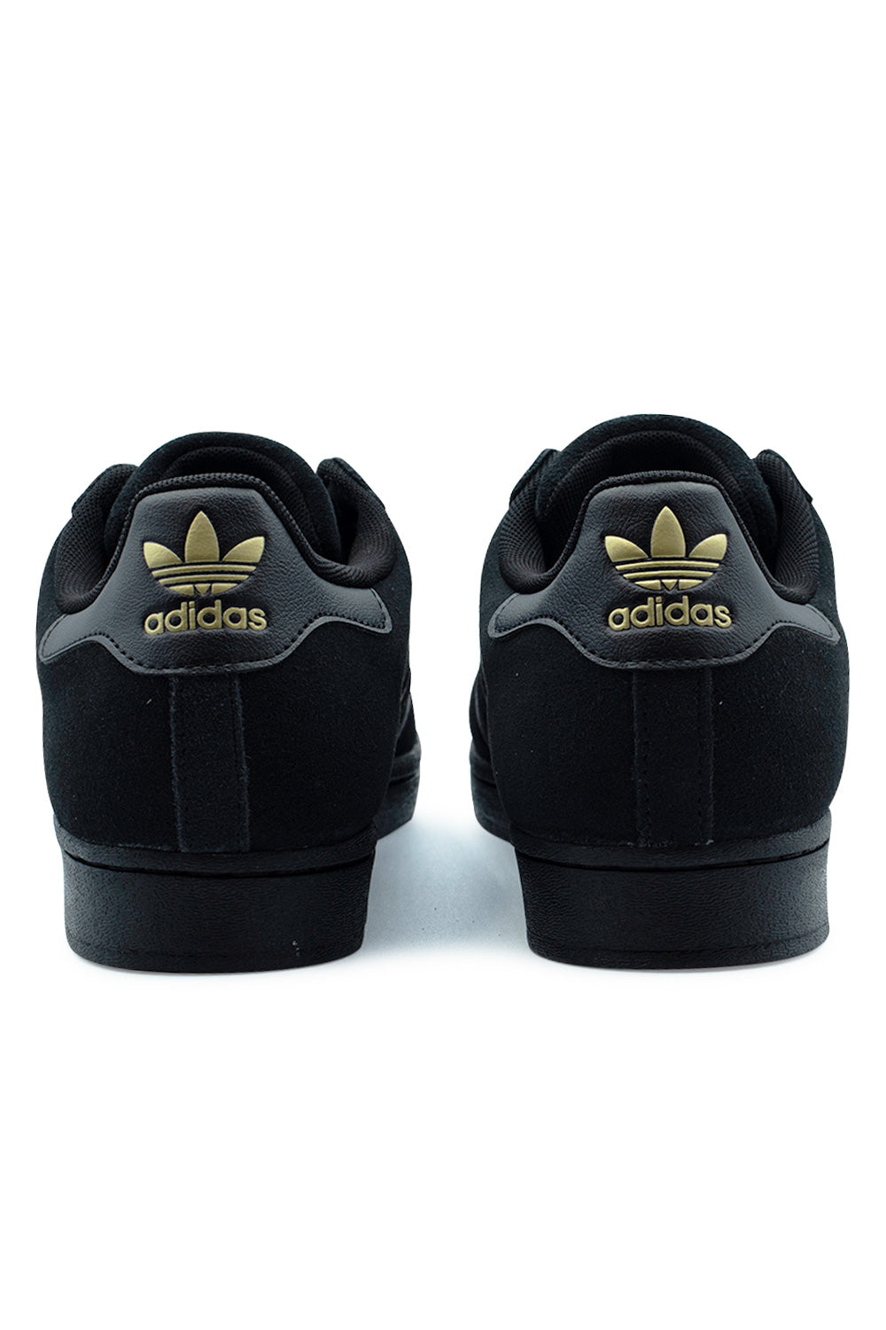 Rear view of the heels of the Adidas Superstar ADV Core Black shoes, displaying the smooth black leather heel tabs printed with metallic gold Adidas Trefoil logos, padded black collars, and solid black rubber cupsole bases.