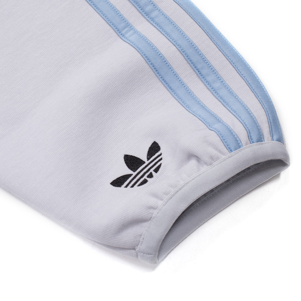 Macro studio perspective of the left sleeve cuff on the adidas x ADWYSD Full Zip Hoodie, showing the sky blue applied Three Stripes, elasticated wrist trim, and a high-density black embroidered classic adidas Trefoil emblem.