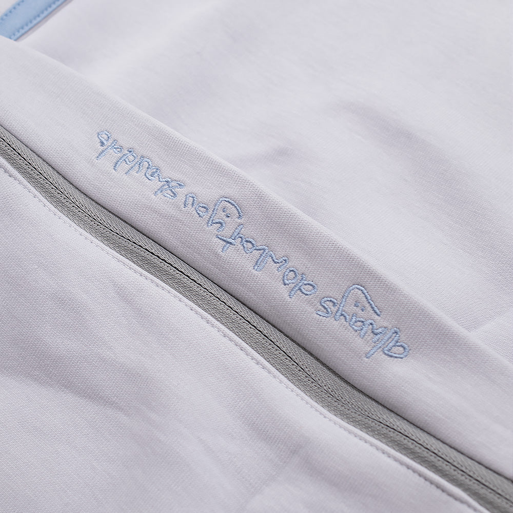 Macro view of the convertible zip-off knee construction on the adidas x Always Do What You Should Do Pant, showing the folded protective fabric overhang embroidered with pastel blue handwritten script reading "always do what you should do" above the concealed horizontal grey nylon zipper track.