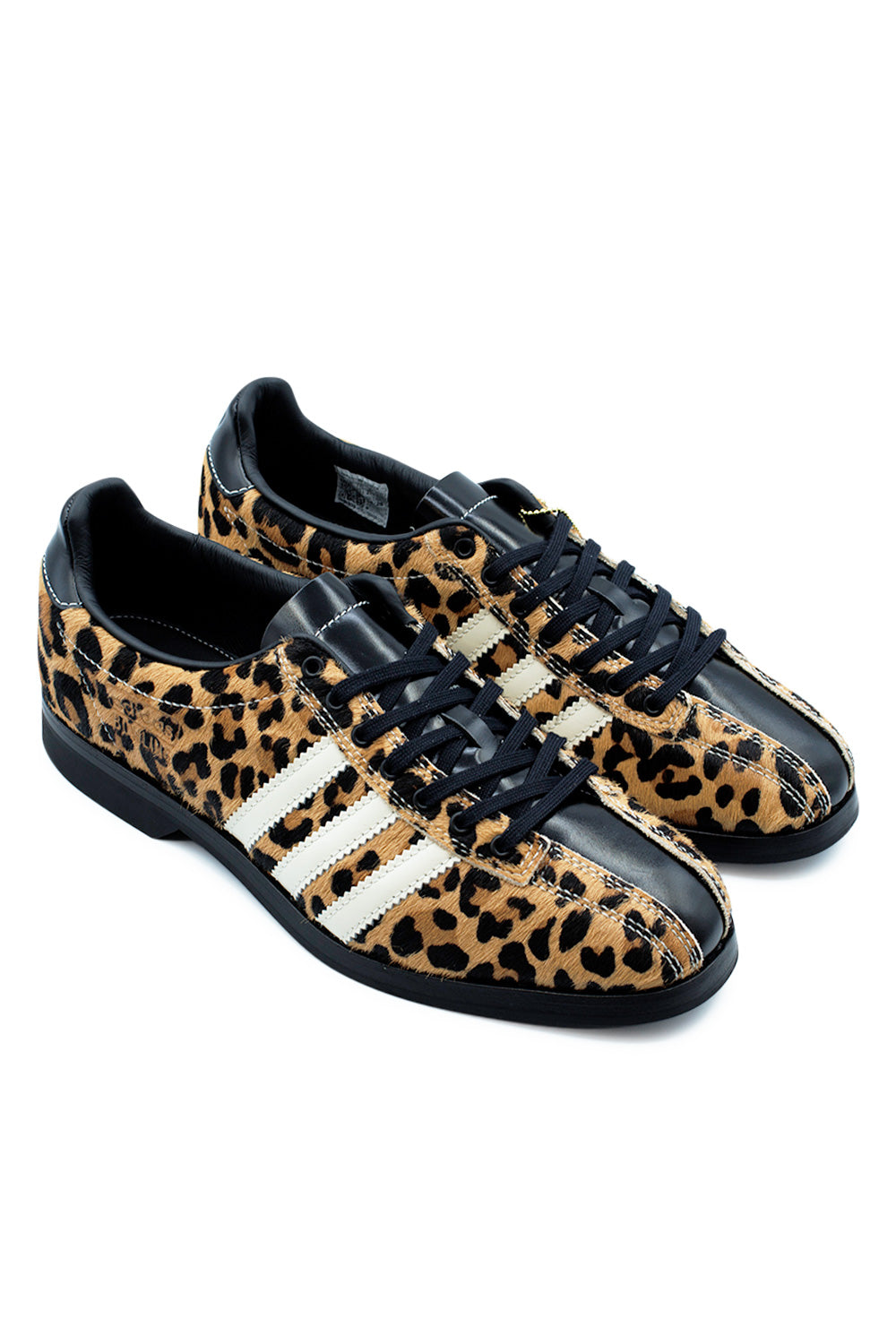 Elevated three-quarter studio perspective of the Adidas X Brain Dead Bowling shoe, illustrating the vintage indoor bowling silhouette, premium black leather collar lining with dual-branded footbeds, and the contrast between fuzzy leopard pony hair and polished black leather.