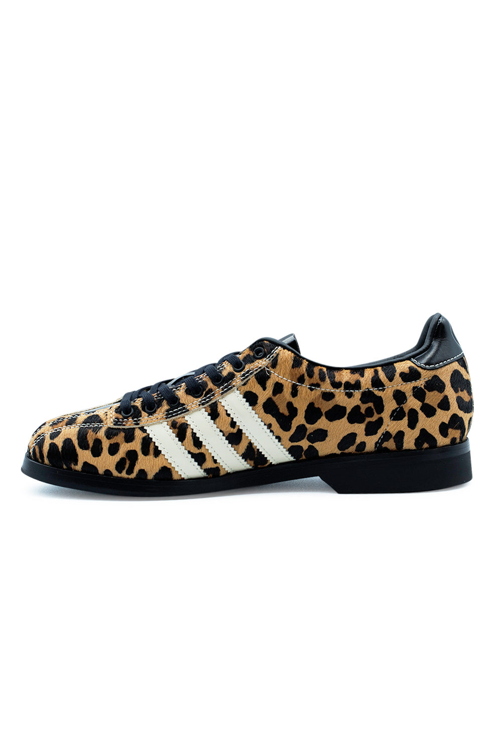 Medial profile shot of the Adidas X Brain Dead Bowling shoe, detailing the uninterrupted cheetah spot pattern on textured calf hair across the arch, three serrated cream leather stripes, reinforced black eyelet facing, and flat low-profile black rubber outsole.