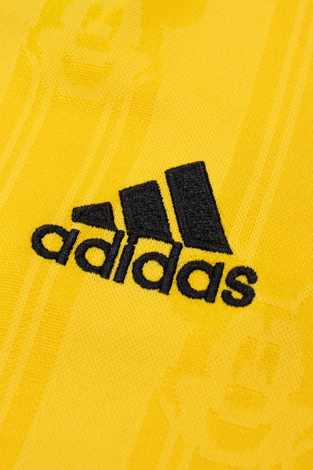 Close-up of the embroidered adidas logo on the chest of the adidas x Brain Dead x Disney Football Jersey Bold Gold showcasing premium embroidery, all over Mickey Mouse pattern and limited World Cup capsule collection craftsmanship