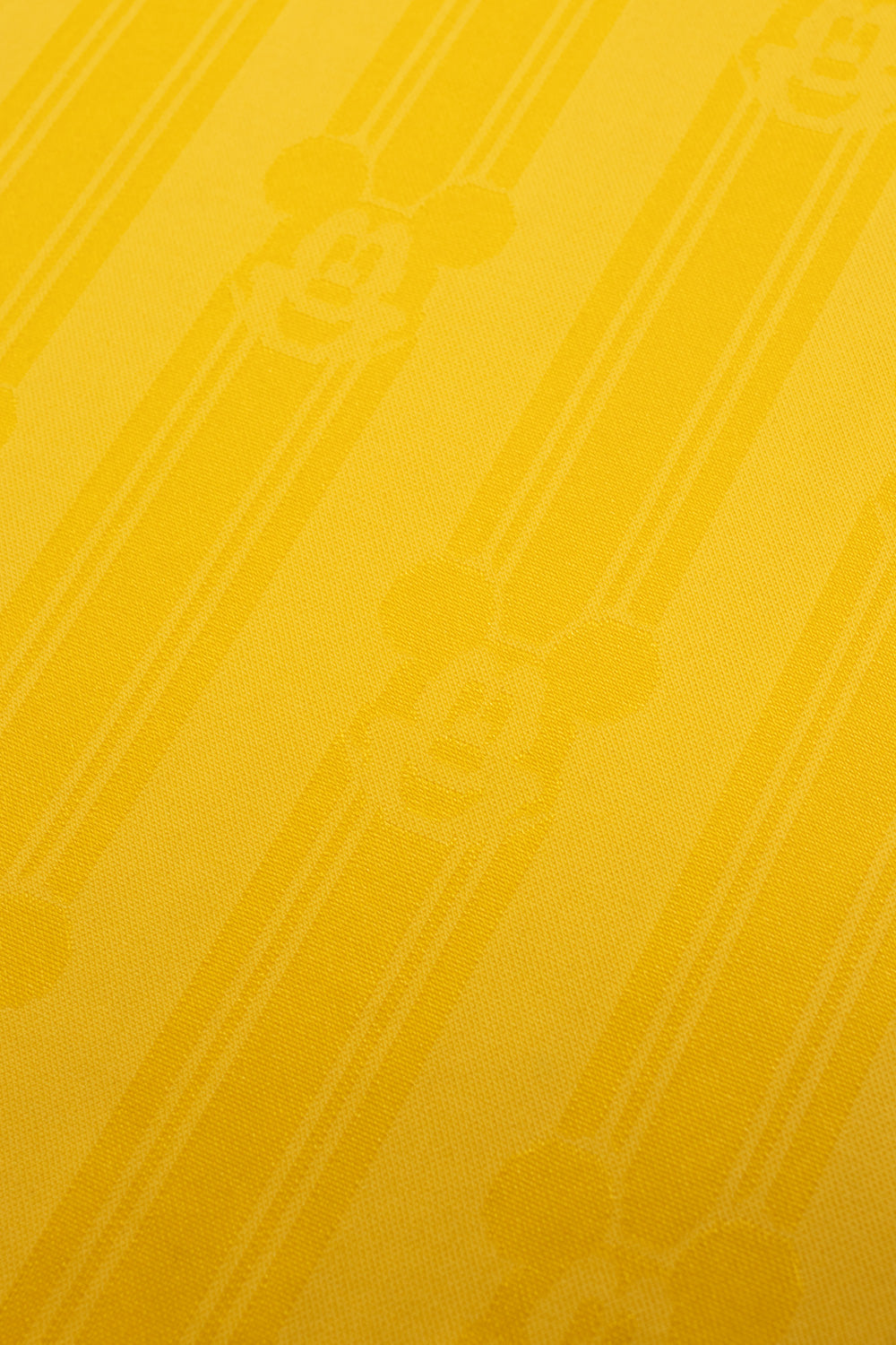 Close-up of the all over woven Mickey Mouse jacquard pattern on the adidas x Brain Dead x Disney Football Jersey Bold Gold showcasing premium textured polyester fabric inspired by classic 90s World Cup football jerseys