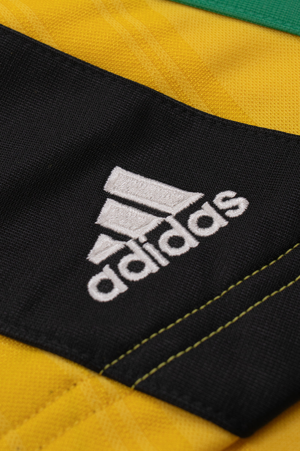Close-up of the embroidered adidas logo on the sewn-on three stripe panel of the adidas x Brain Dead x Disney Football Short Bold Gold showcasing premium embroidery, retro football inspired design and exclusive World Cup capsule collection craftsmanship
