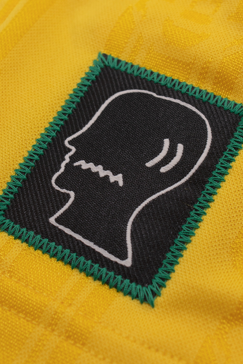 Close-up of the embroidered Brain Dead logo patch on the adidas x Brain Dead x Disney Football Short Bold Gold featuring premium woven patch construction, all over Mickey Mouse pattern and exclusive collaborative branding