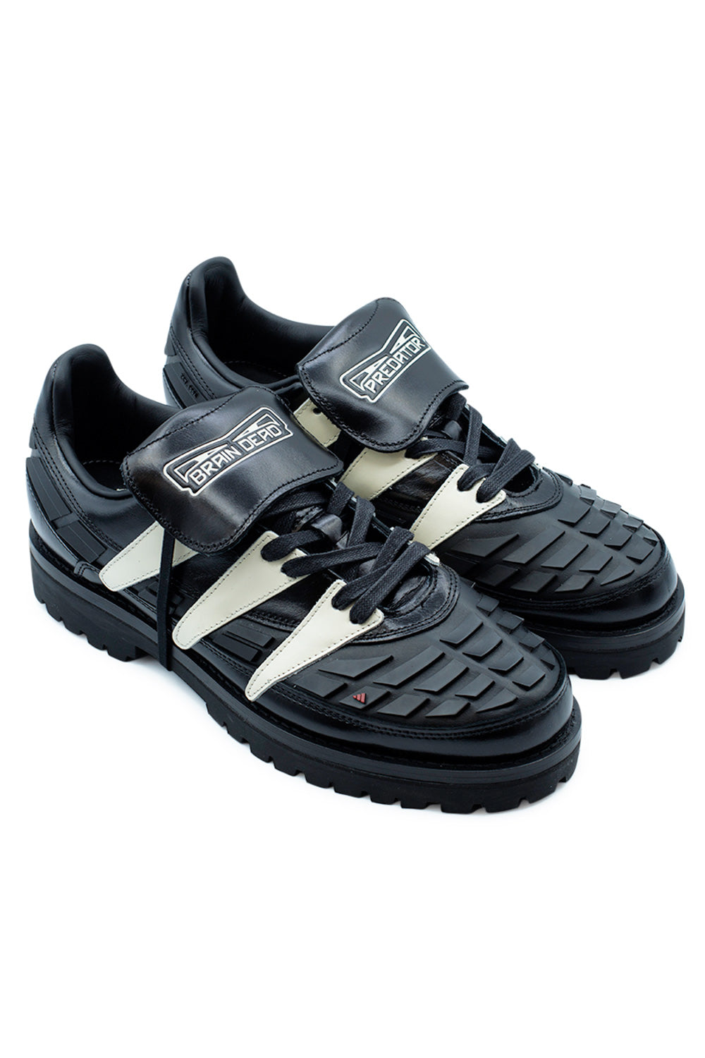 Angled view of the Adidas Originals x Brain Dead x Disney Predator featuring black leather, Crystal White Three Stripes, aggressive lug outsole, removable tongue system, molded Predator overlays and elevated streetwear design inspired by the legendary Predator 94 football boot.