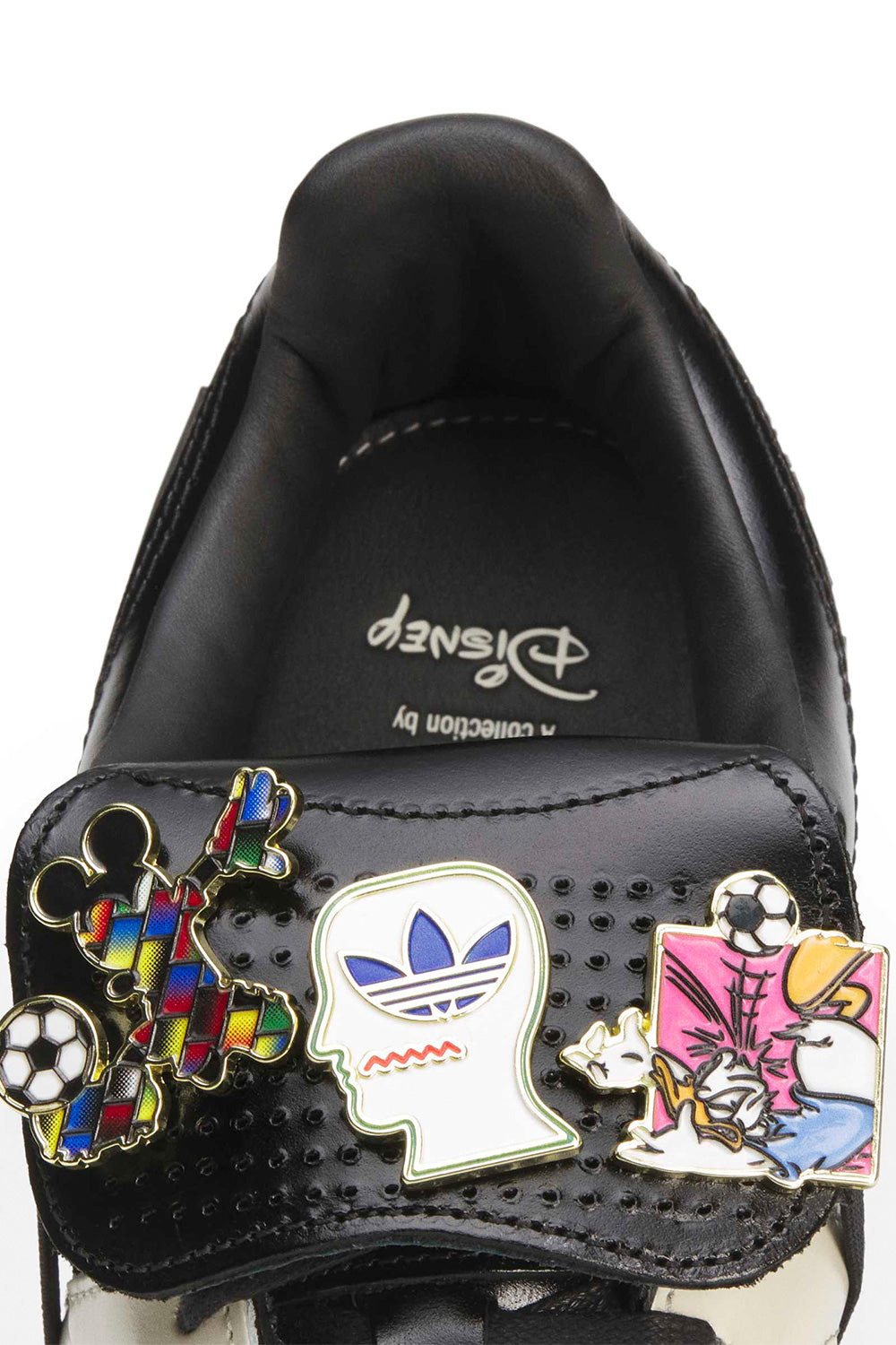 Close-up of the removable Disney enamel pins attached to the interchangeable Predator tongue, featuring Donald Duck, Mickey Mouse, adidas Trefoil and Brain Dead graphics that customize the limited Adidas Originals Predator collaboration sneaker.