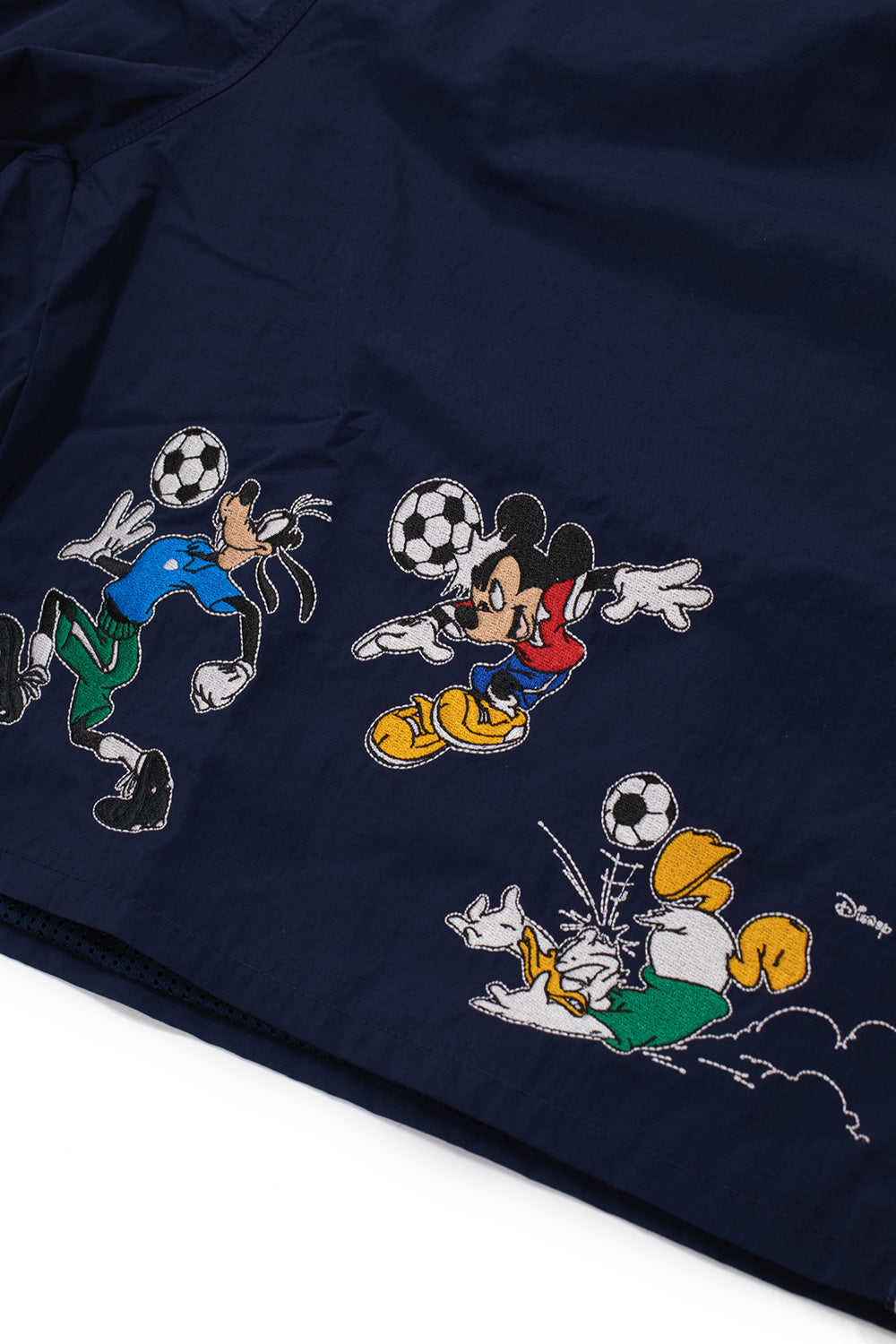 Close-up of the seven-color embroidered Mickey Mouse, Goofy and Donald Duck football artwork on the adidas x Brain Dead x Disney Short Core Navy from the limited adidas x Brain Dead x Disney World Cup capsule collection