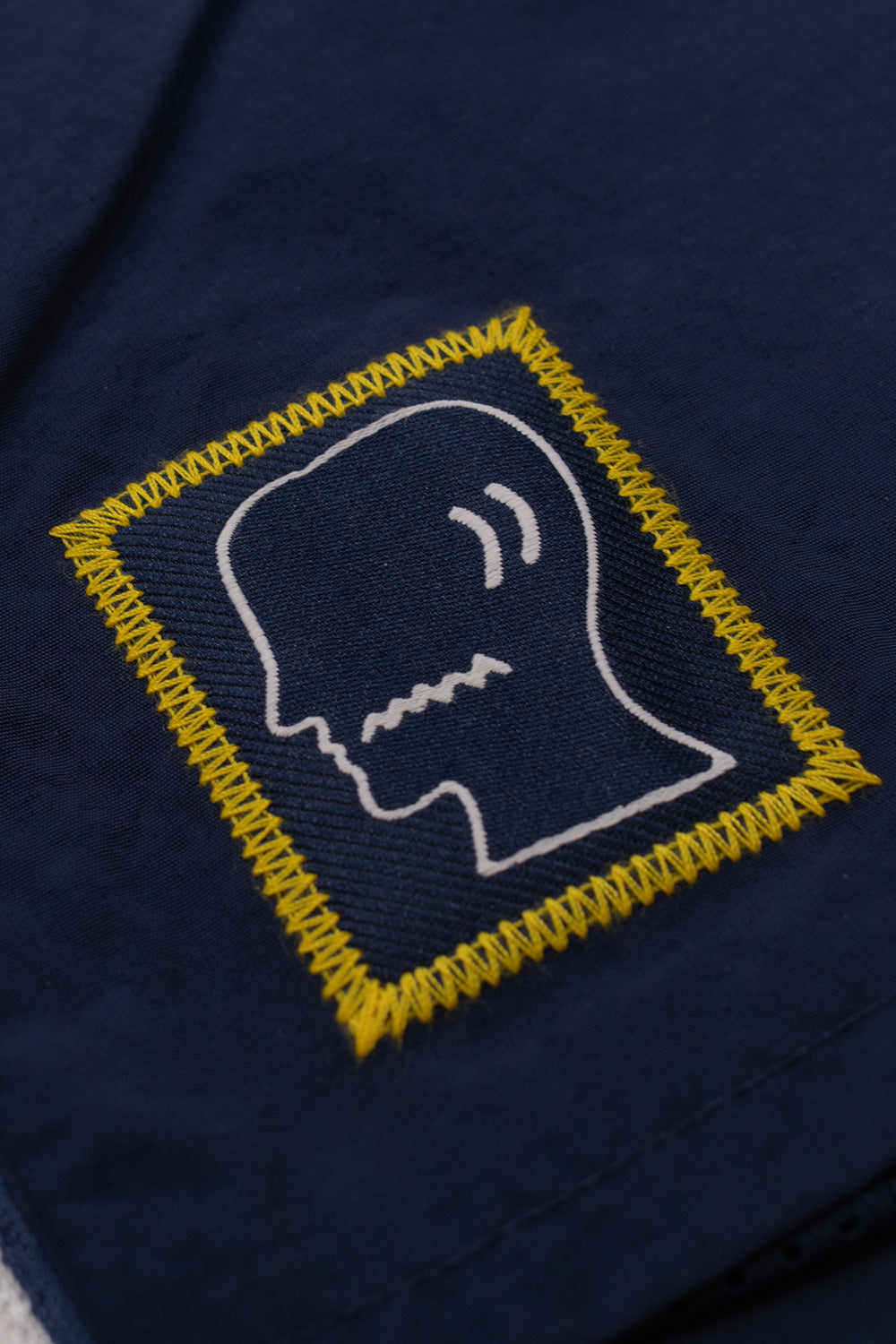Close-up of the embroidered Brain Dead logo patch on the adidas x Brain Dead x Disney Short Core Navy featuring premium stitching and exclusive collaborative branding inspired by 90s World Cup football culture