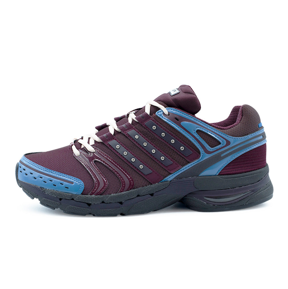Lateral side view of the Adidas X Hardies Adistar Control 5 sneaker in Aurora Ruby, Maroon, and Dusky Ink, showcasing breathable wine-red mesh uppers, glossy synthetic overlays, slate blue support cages, sparkling rhinestone-studded Three Stripes, and a sculpted black cushioned running midsole.